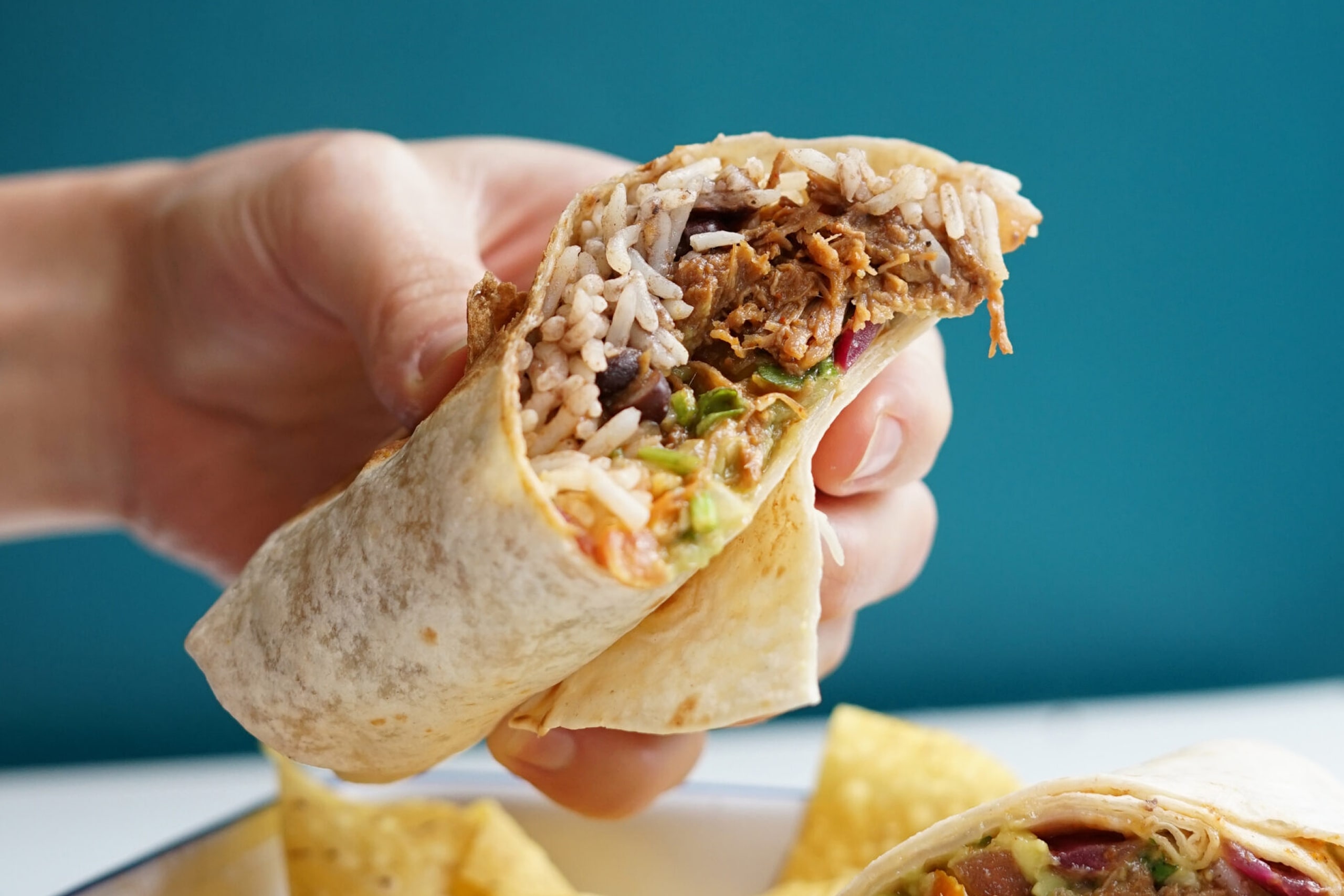 Mexican beef burrito filled with rice, wrapped in a soft tortilla, garnished with fresh toppings.