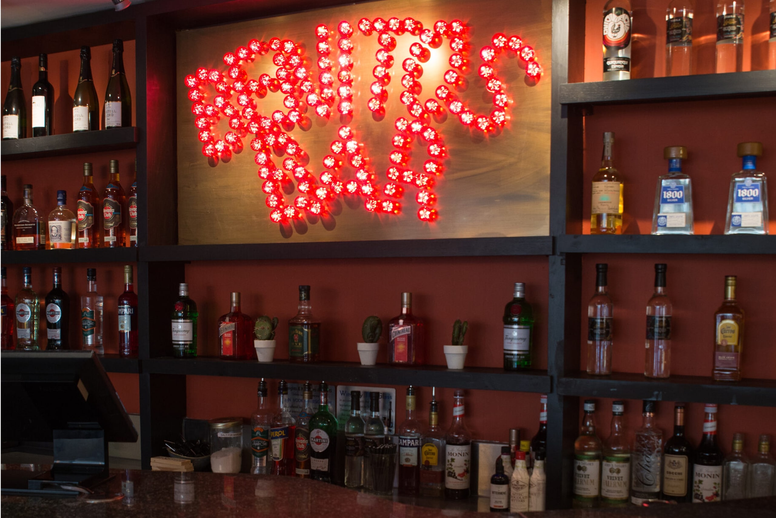Benito's Bar sign hanging above a lively bar, inviting patrons to enjoy drinks and socialize.