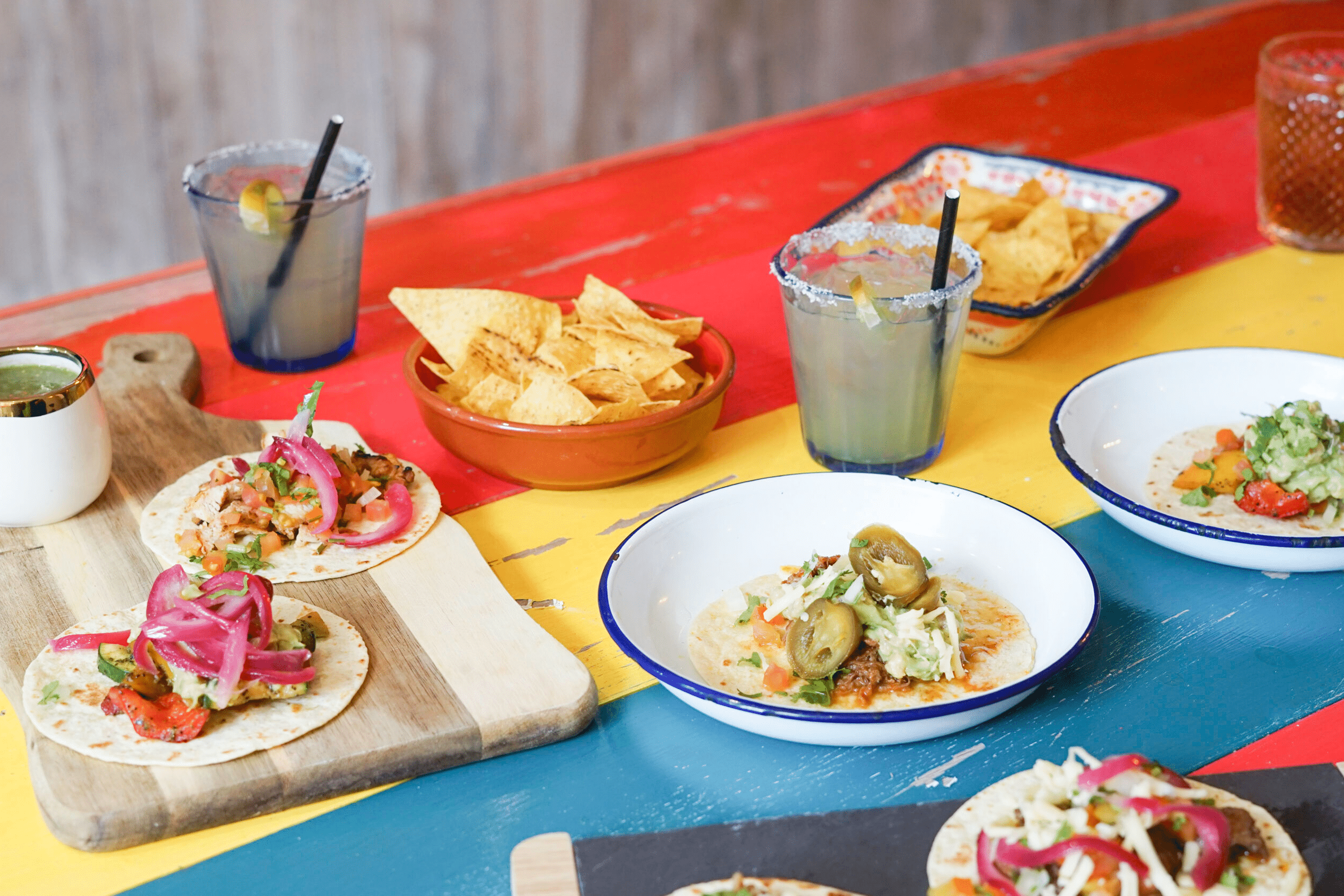 A colourful spread of Mexican food across a red, yellow and blue table