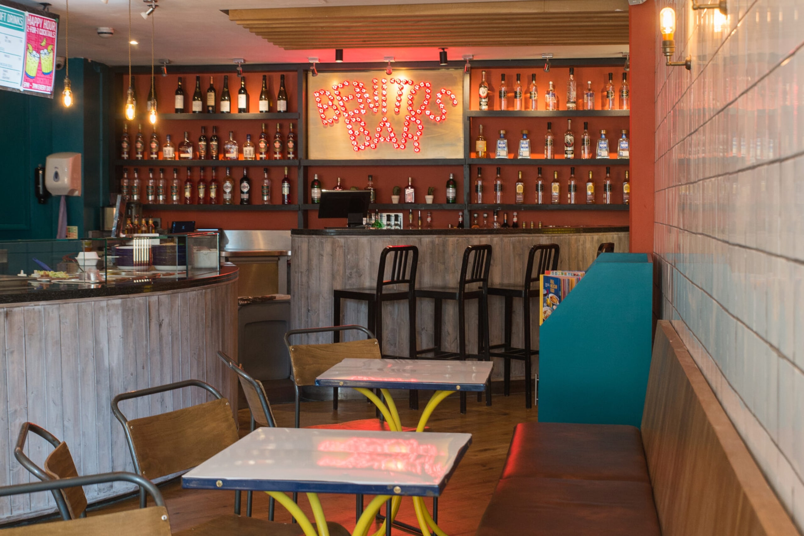 A cozy restaurant featuring a stylish bar area with seating and drinks on display.