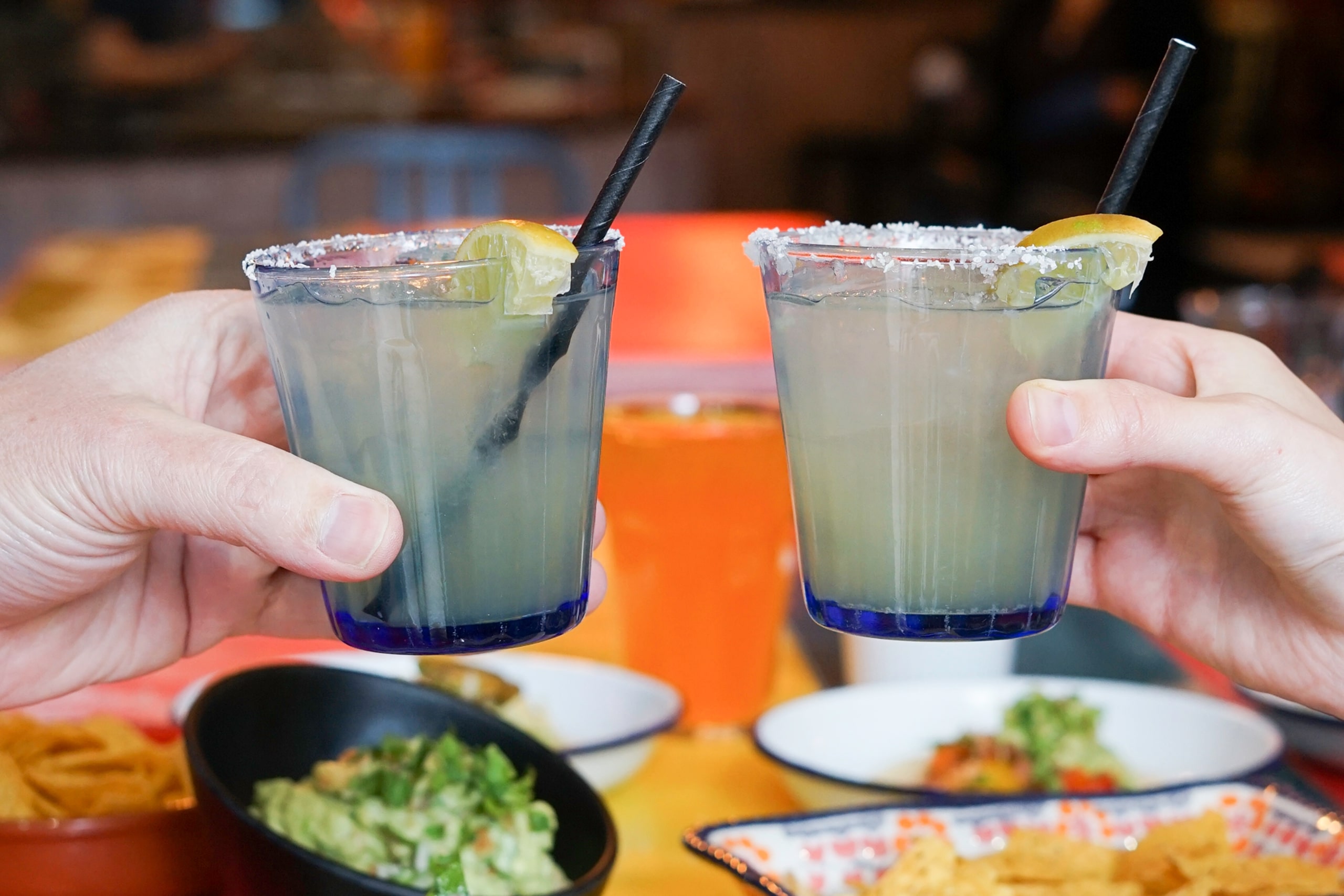 Close up of two people holding a drink, ready to cheers